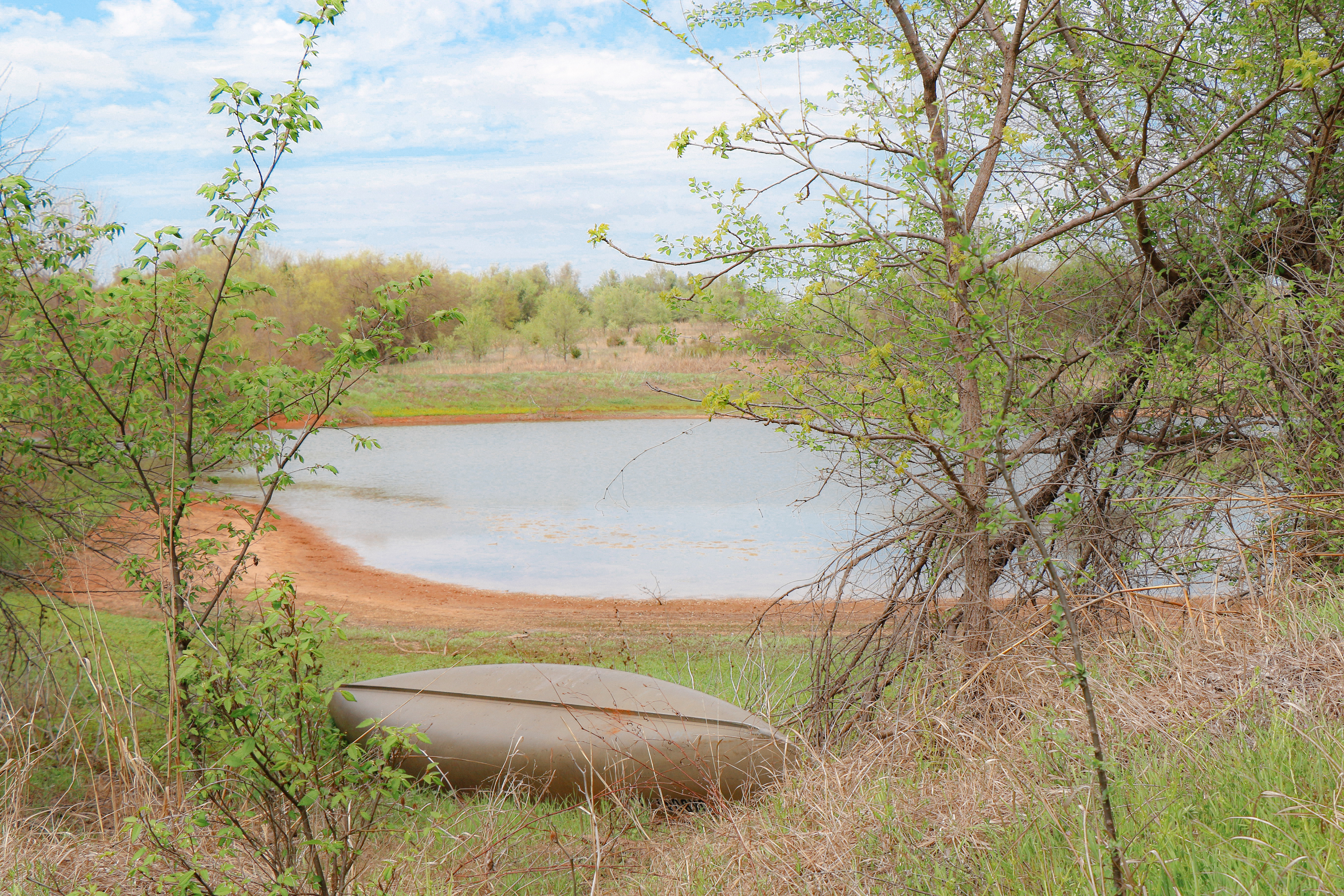 Outdoor view of pond and a turned over kayak.