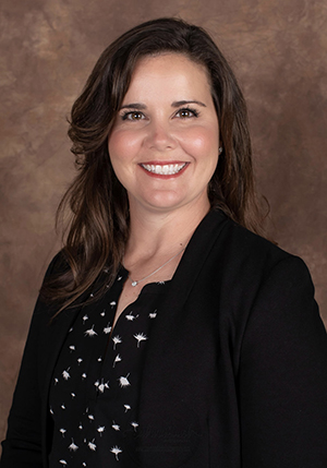 Regent Amanda Conley facing the camera. She is wearing a black and white polka dot shirt with a black jacket over it. 