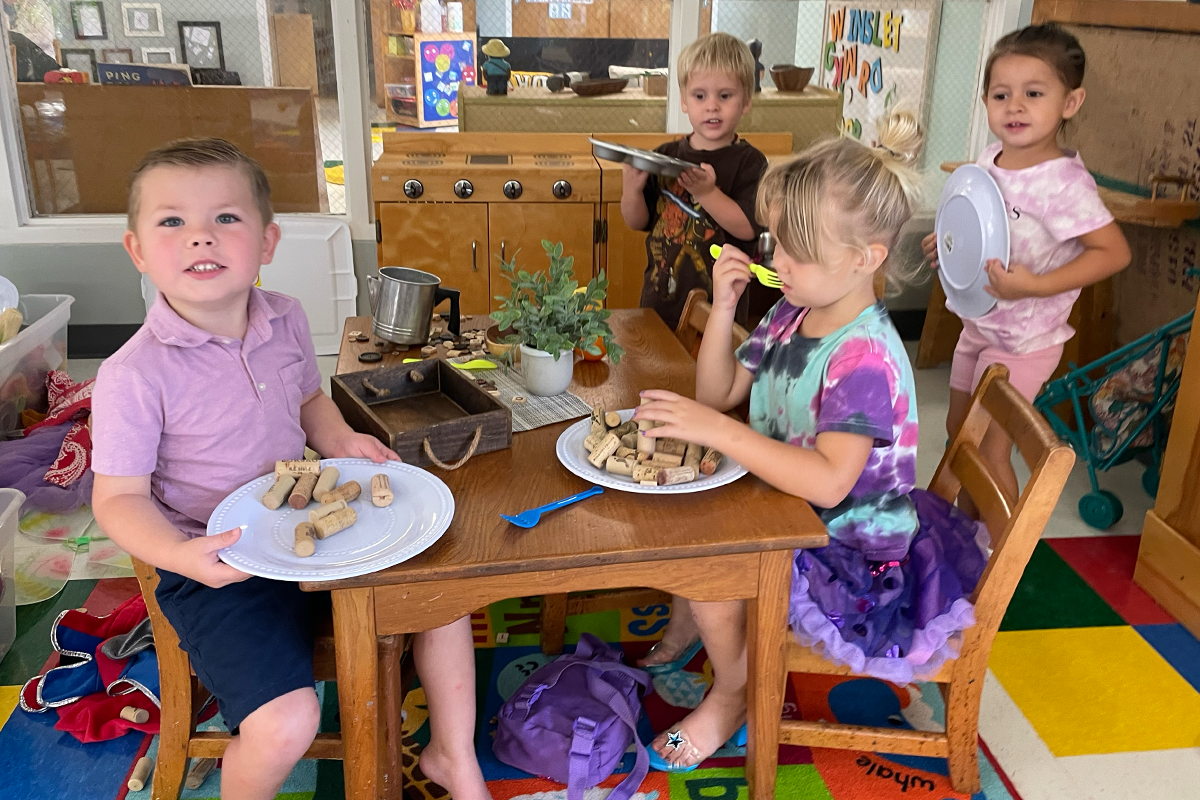 children sitting around a table and pretend eating