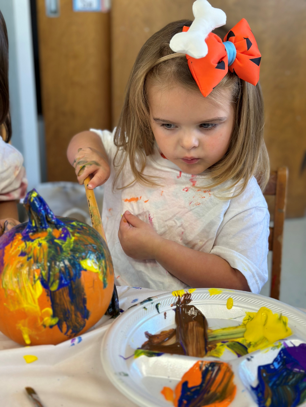 A child painting a small pumpkin.
