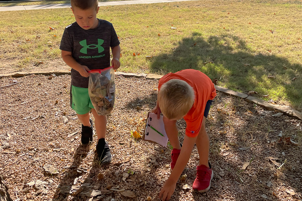 two boys picking up rocks and items outside