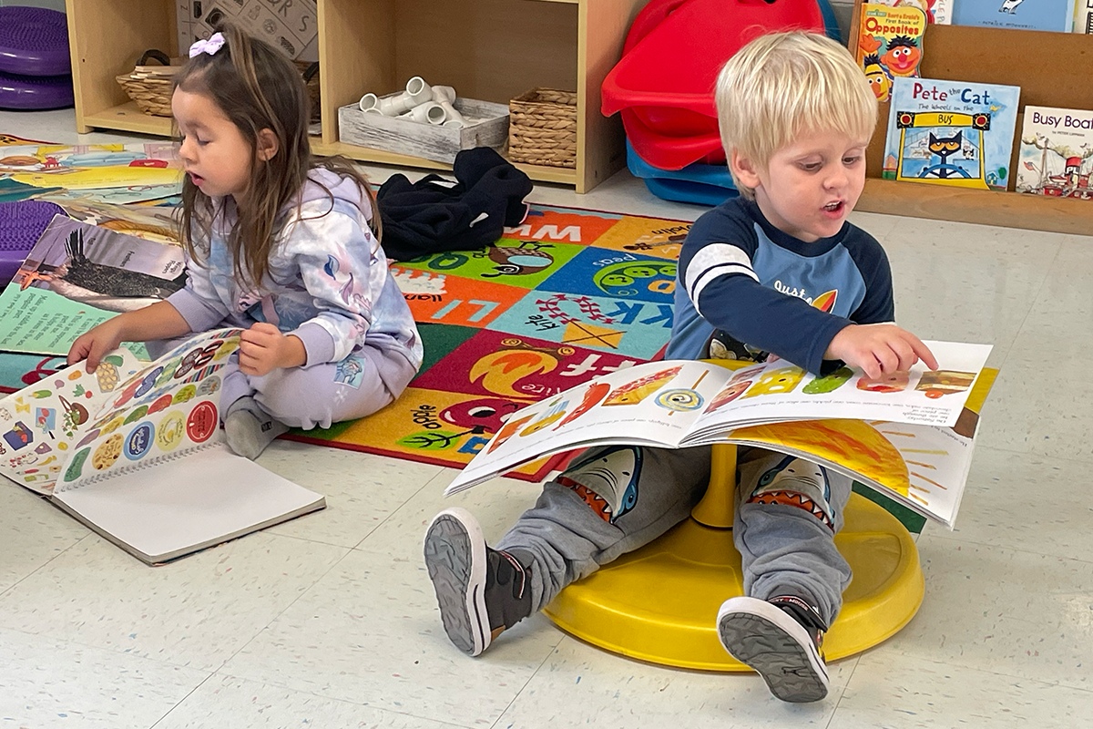 two children sitting down and reading books