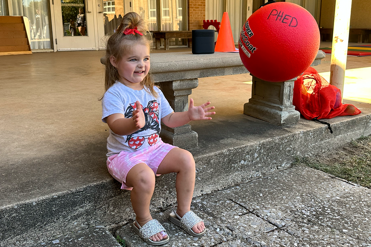 young girl sitting down catching a ball