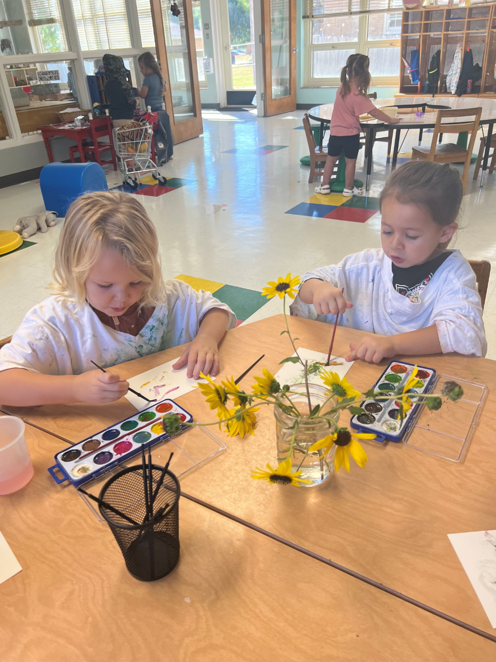 Children using watercolor paints at a table.