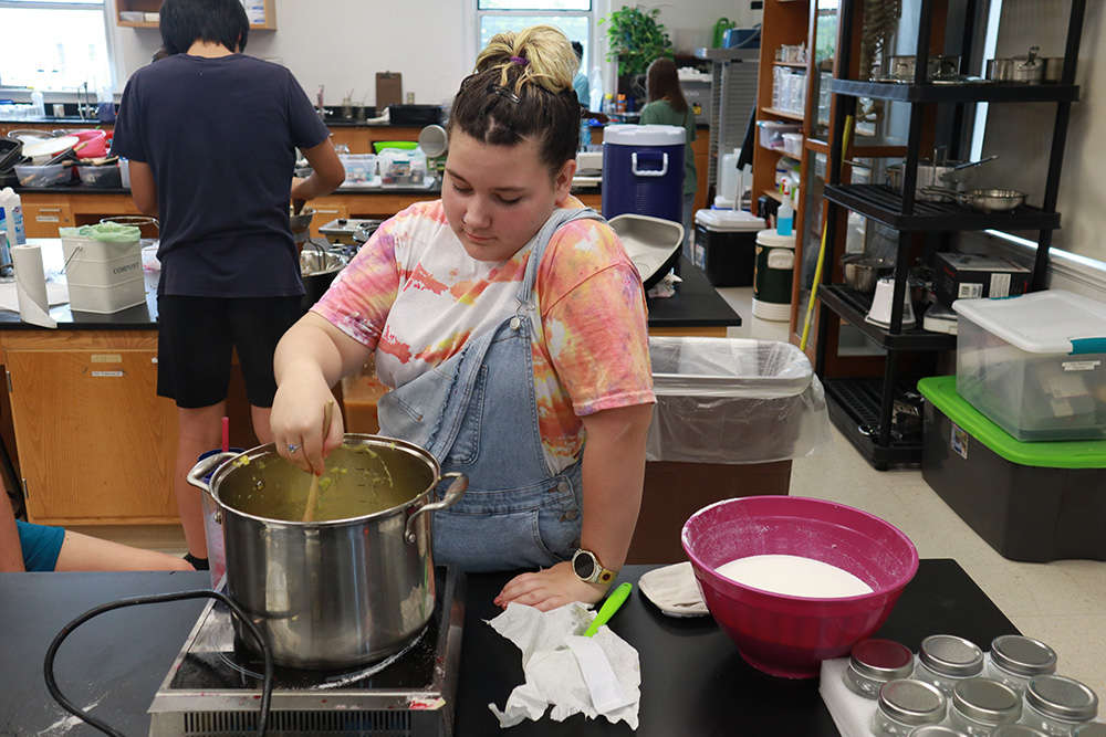 A student mixes in a large pot