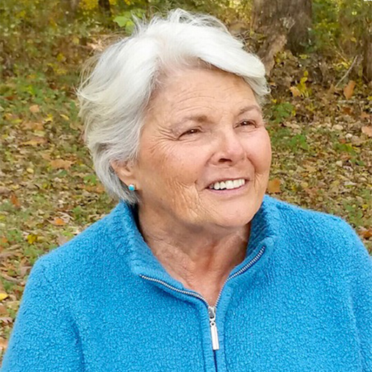 Woman with white hair and a blue jacket outside in the fall