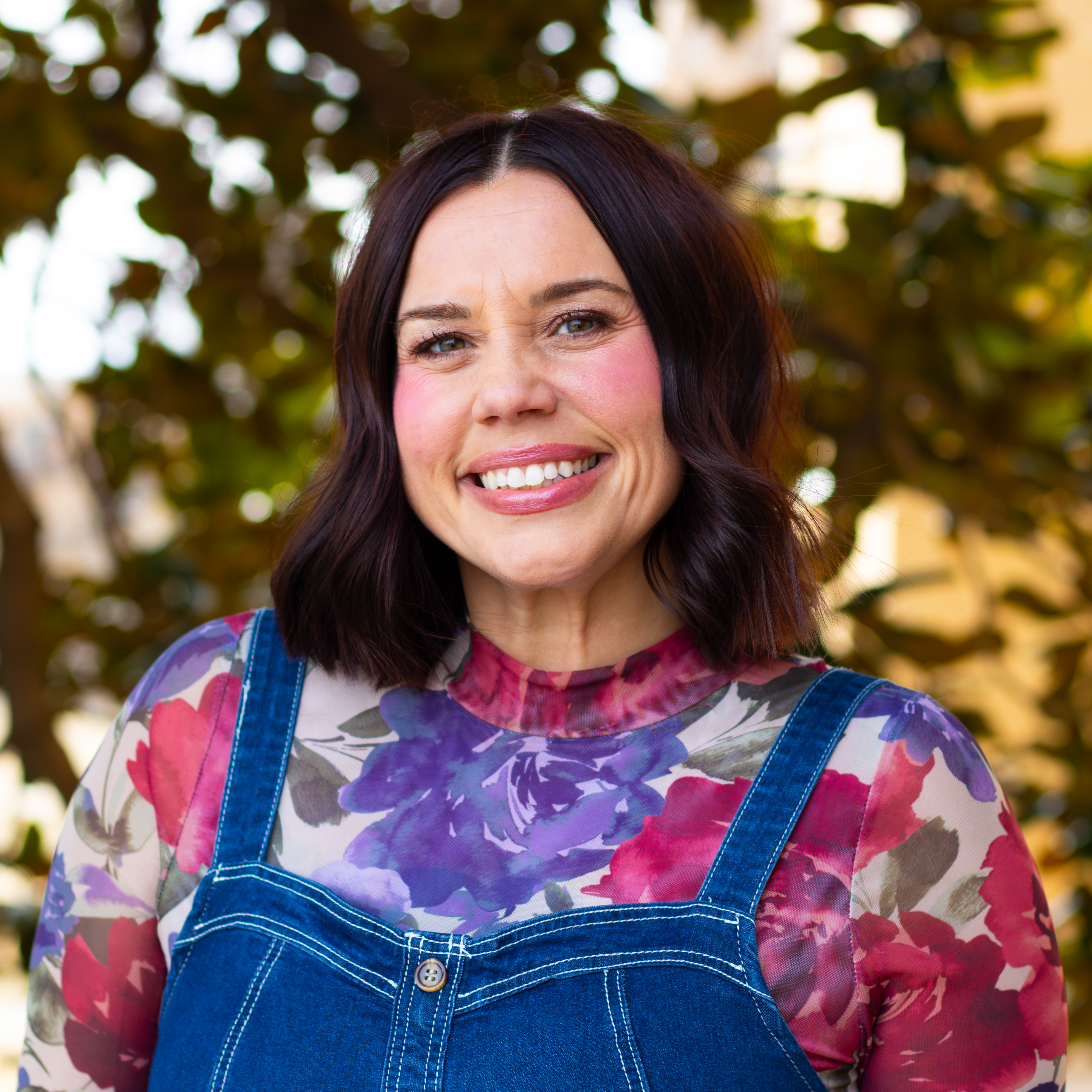 Woman smiling in adorable floral shirt and overalls