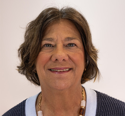 Woman with wavy brown hair waring a grey sweater