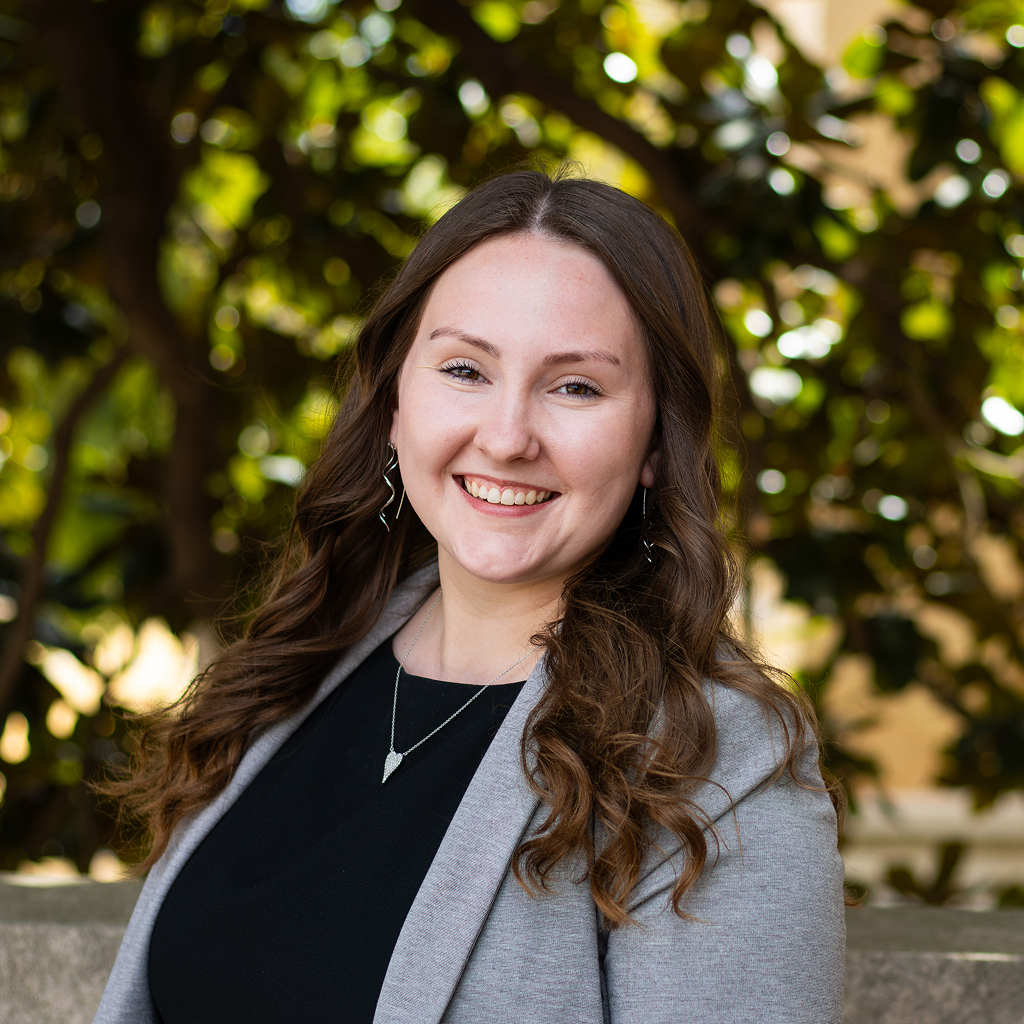 Woman with wavy hair wearing black shirt under gray suit