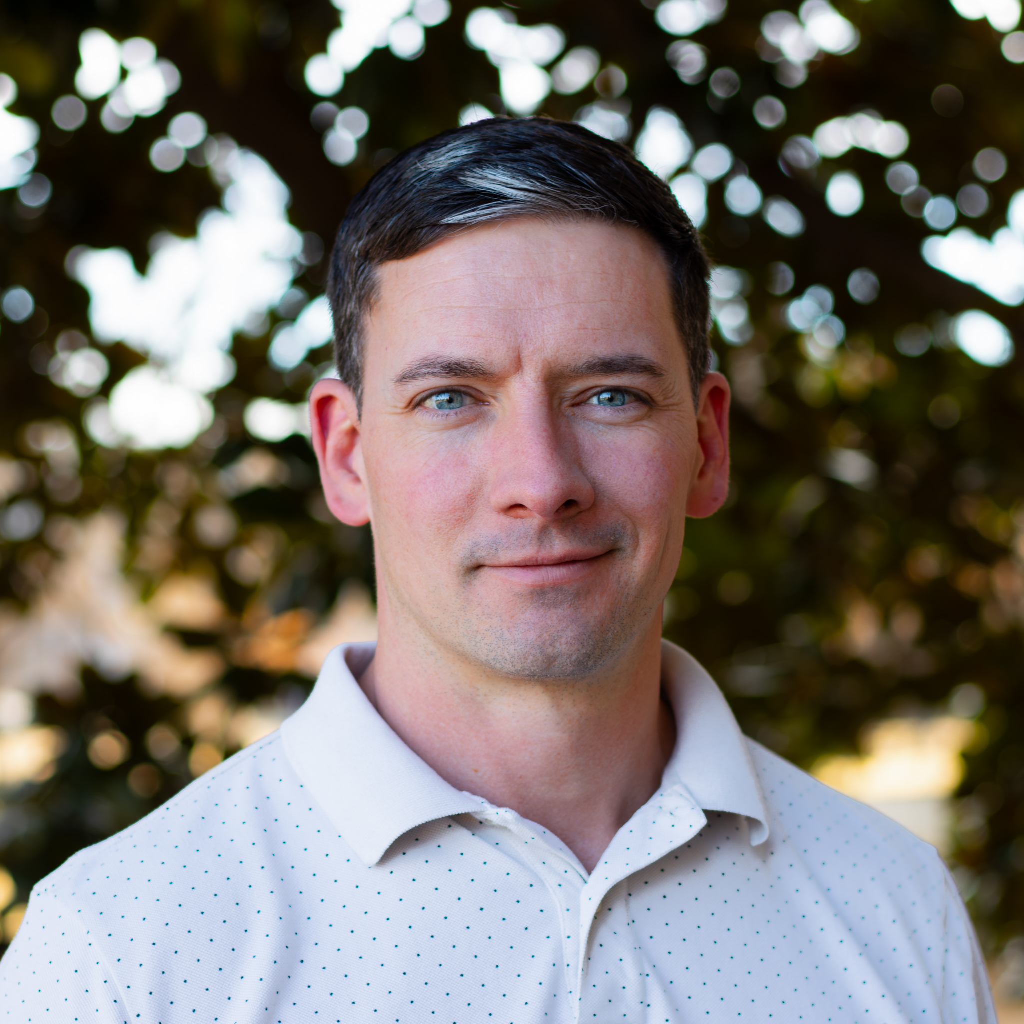 man with blue eyes and white polo