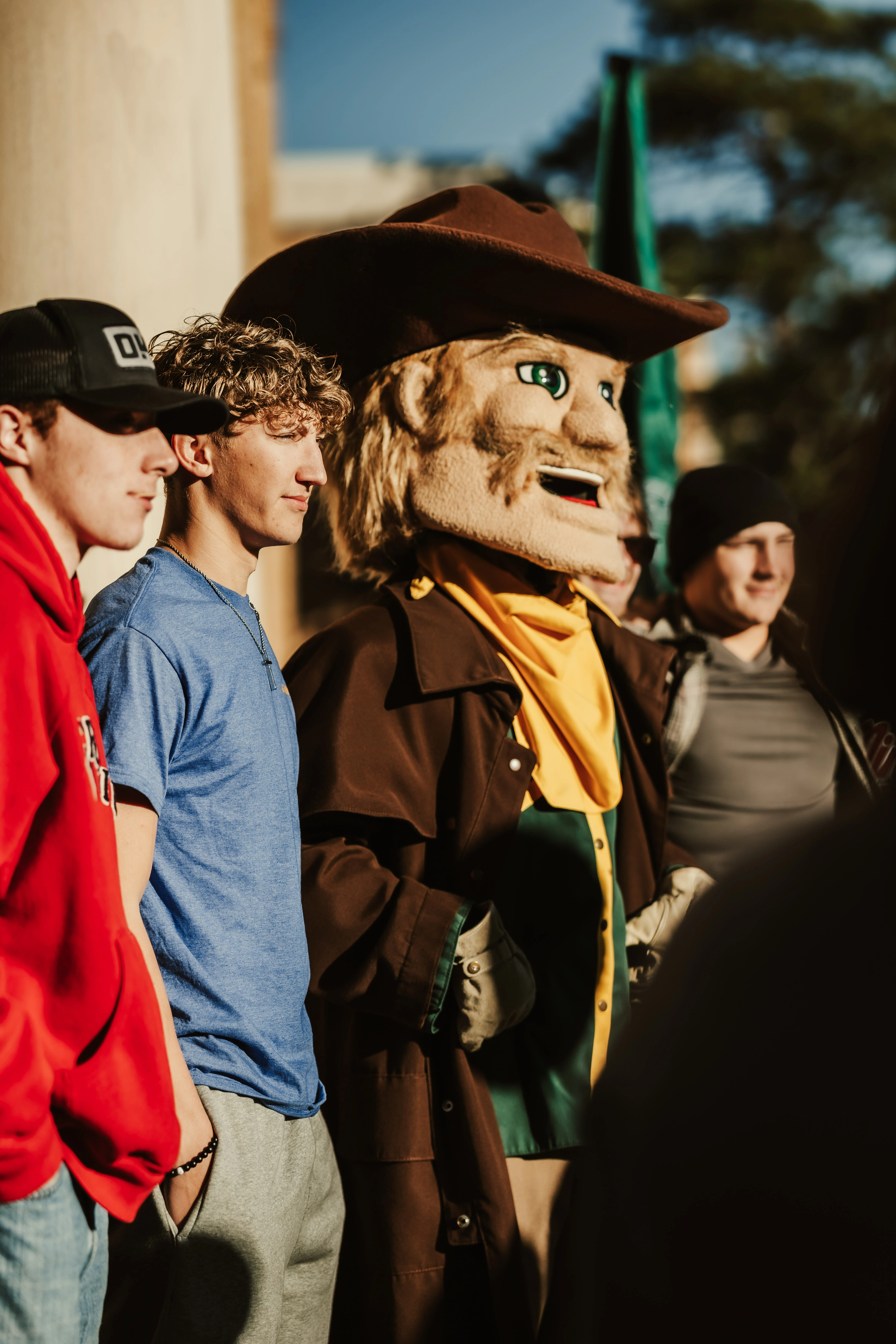 USAO’s Drover mascot poses with students outdoors on campus.