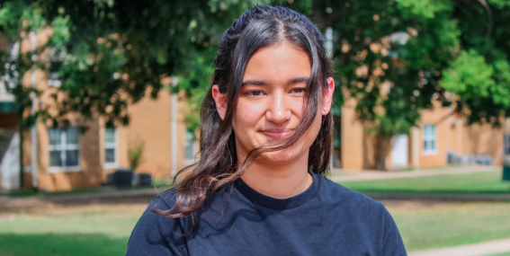 Rachel Dennis wearing a black shirt, sitting outside on campus smiling.