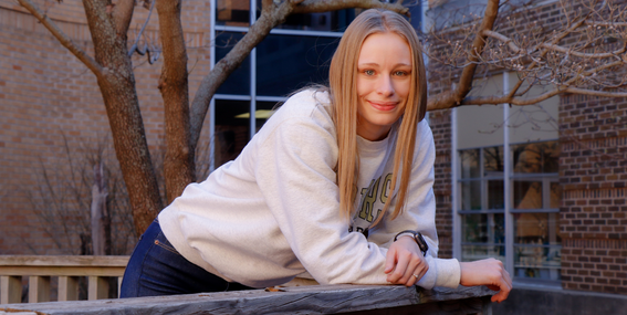 Holly Dunivan resting her arms on a railing and smiling to the camera.