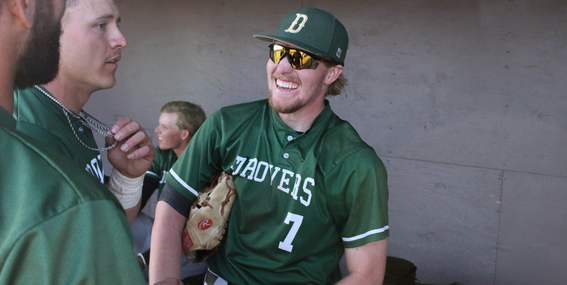 Luke Lewis smiling and laughing with other baseball players in the dugout.
