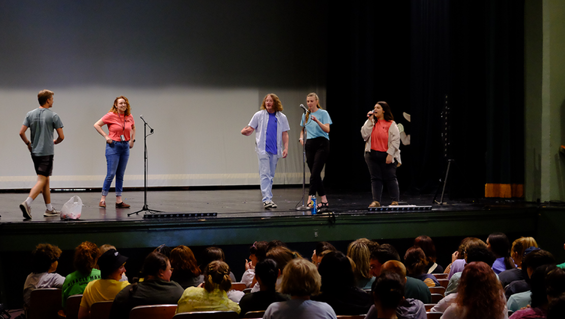Five students on the stage in Te Ata Auditorium during a session of the 2022 new student orientation. 
