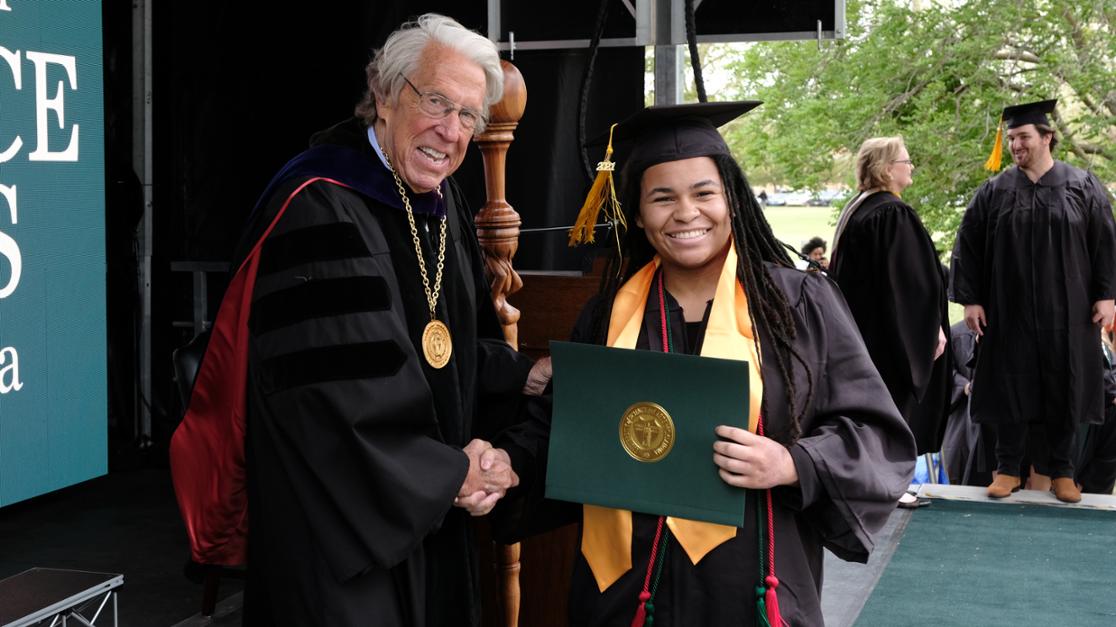 A photo of President Feaver in full academic regalia speaking at the podium during last year's commencement