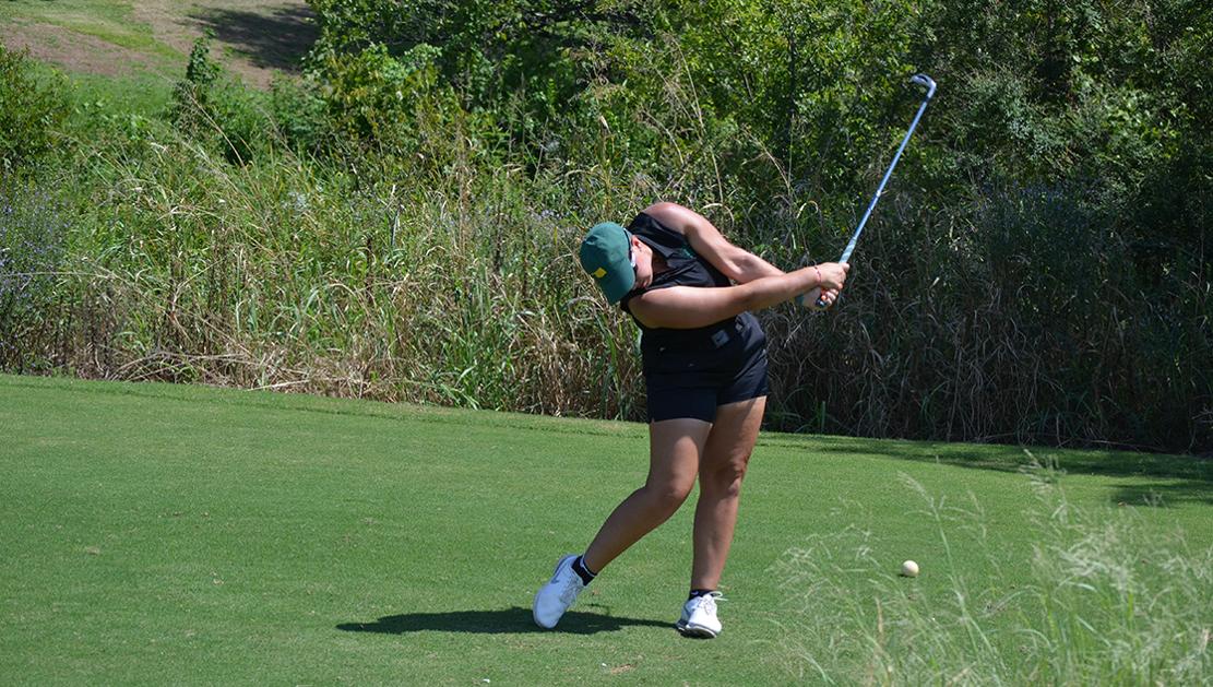 A photo of riddle in the middle of a golf swing in her Drover Golf uniform