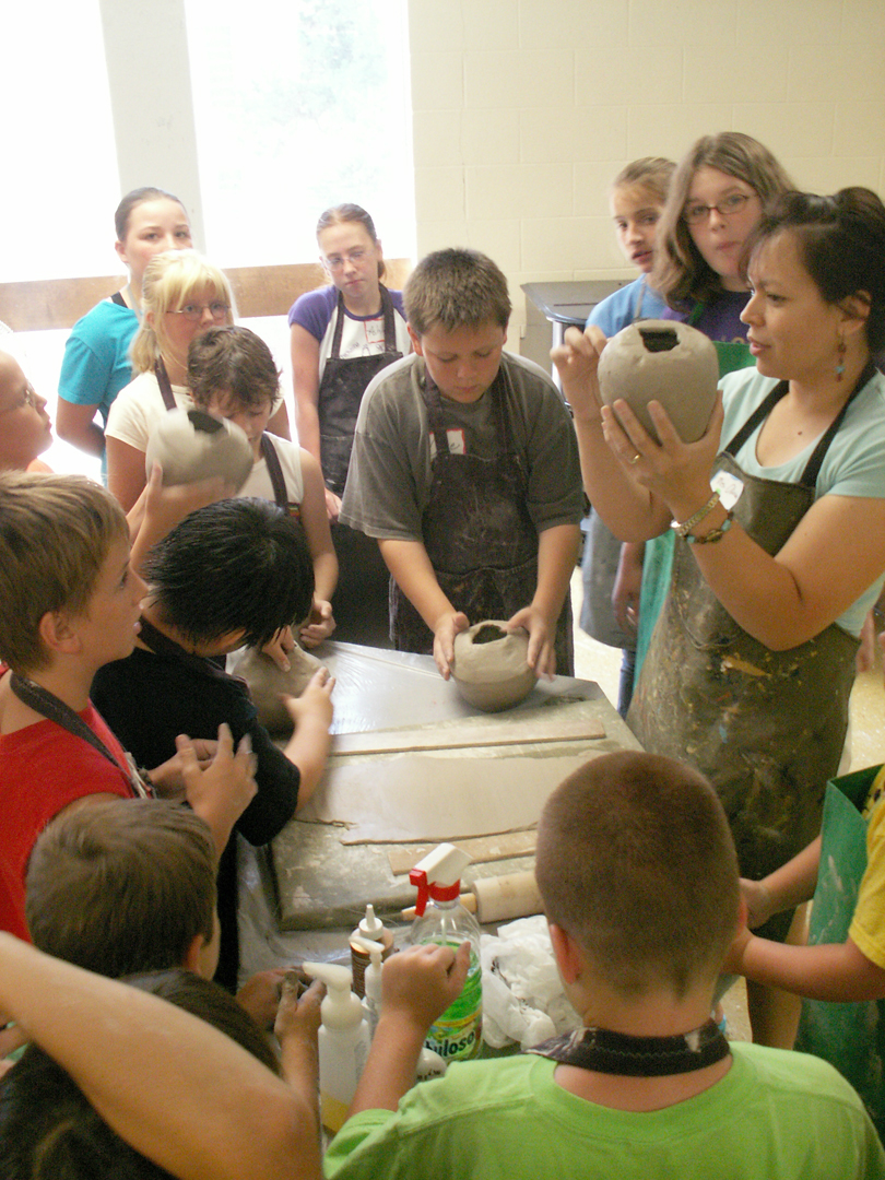 students gathered around for a pottery lesson