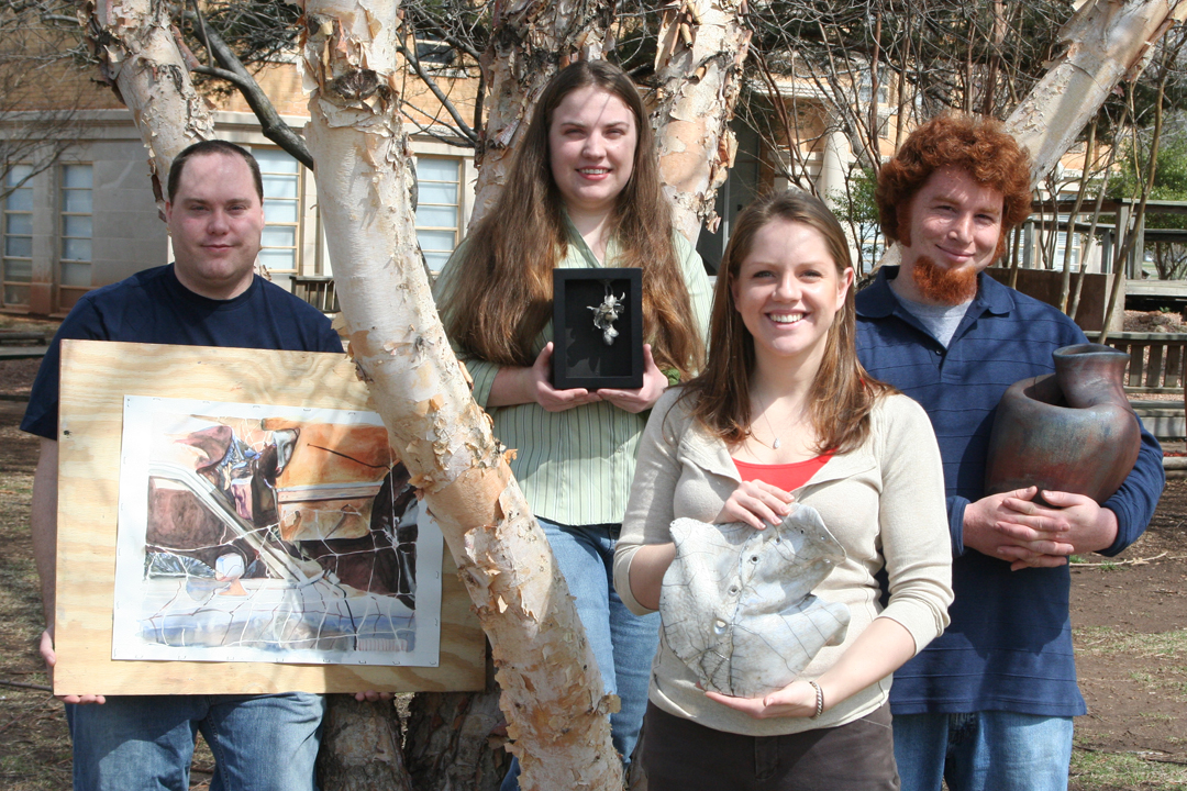 Four students gathered around their artwork