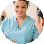 Nurse holding a clipboard talking to a patient.