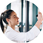 A woman writing ideas on a transparent glass board using a black marker.